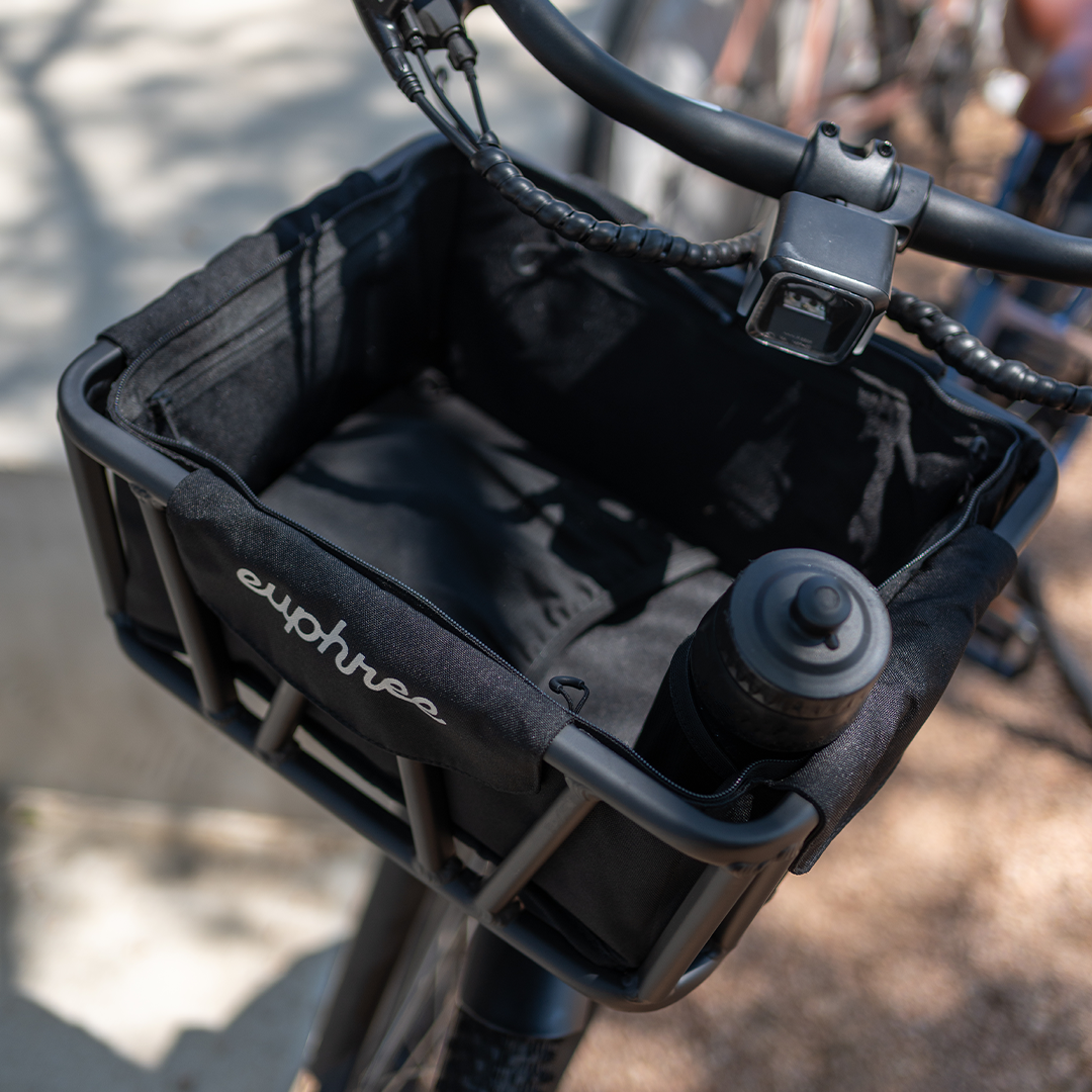 Close-up view of the Euphree Front Basket Liner compartments, showcasing a water bottle securely stored inside. The liner features zippered compartments and dedicated pockets for easy organization and protection of valuables during rides.