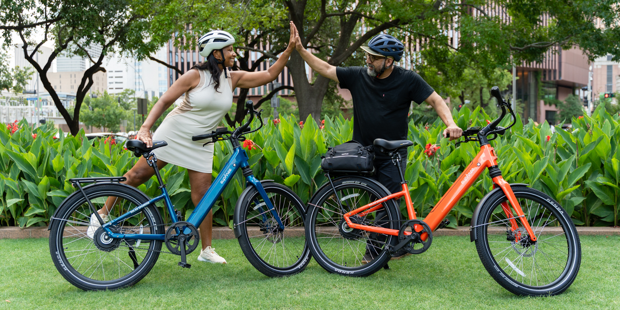 Couple high fiving at the park with Solar Sparrow ebikes in Riviera Blue and Canyon Flame