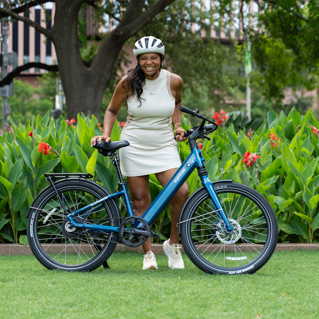 Happy rider posing with her Riviera Blue Solar Sparrow at the park—lightweight step-through electric bike for everyday joy